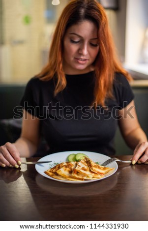 Woman eating delicious quesadilla in restaurant. Young redheaded woman is eating Mexican food in a cafe