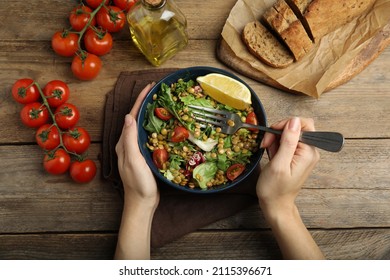 Woman Eating Delicious Salad With Lentils And Vegetables At Wooden Table, Top View