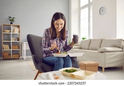 Woman Eating Delicious Takeout Lunch At Home. Happy Lady Sitting In Armchair In Living Room, Drinking Coffee, Holding Food Container On Lap, And Enjoying Tasty Veggie Salad From From Takeaway Delivery