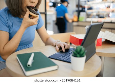 Woman eating donuts and working on tablet at cafe - Powered by Shutterstock