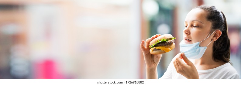 Woman Eating Fastfood Burger In Face Mask At Restaurant