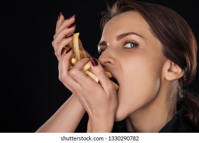 Woman Eating French Fries While Looking At Camera Isolated On Black