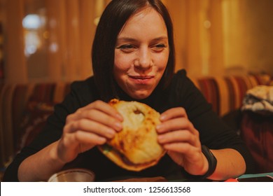 Woman Eating French Hamburger. Portrait Of Student Consume Fast Food On Table. Girl Trying To Eat Junk. Advertise Fast Food On Daek Background. Student Eats Semi-finished Products.
