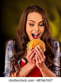 Woman Eating French Hamburger. Portrait Of Student Consume Fast Food On Table. Girl Trying To Eat Junk. Advertise Fast Food On Daek Background. Student Eats Semi-finished Products.