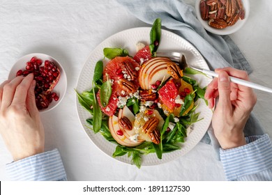 Woman eating Fruits citrus salad with nuts, green lettuce leaves. Balanced food. Top view of hands with plate of meal of Spinach with orange, grapefruit, apples, pecans - Shutterstock ID 1891127530
