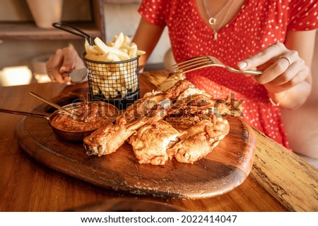 Woman is eating grilled tabaka chickens with tkemali sauce in a traditional Georgian rustic restaurant