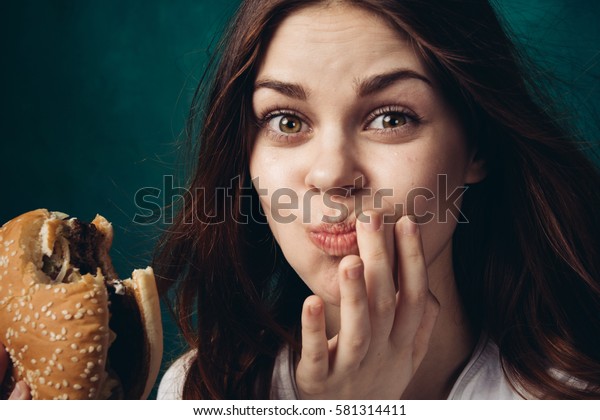Woman eating a hamburger, chewing a hamburger,\
hamburger in hand