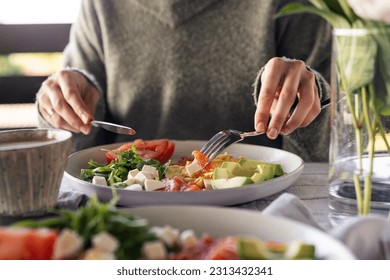 Woman eating healthy morning meal. Healthy breakfast with salmon, omelet, avocado, fresh herbs, cheese and tomatoes