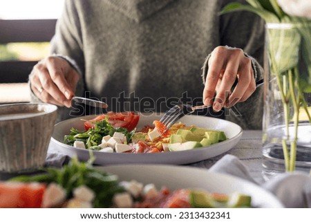 Woman eating healthy morning meal. Healthy breakfast with salmon, omelet, avocado, fresh herbs, cheese and tomatoes