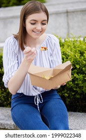 Woman Eating Healthy Vegan Or Vegetarian Takeaway Lunch From Recyclable Packaging With Wooden Fork