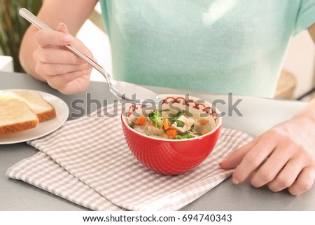 Woman eating homemade chicken soup on table
