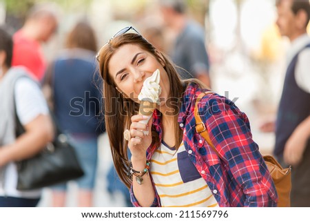 Woman eating Ice cream on vacation travel. Smiling girl having fun eating icecream outdoors during holidays in Europe. 