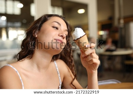 Woman eating an ice cream sitting in a coffee shop interior