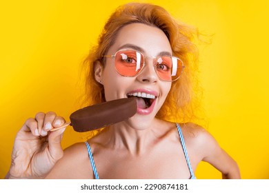 woman eating icecream isolated on yellow. woman with icecream in studio. woman with icecream