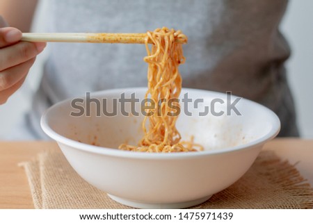 Woman eating instant noodle in white bowl.