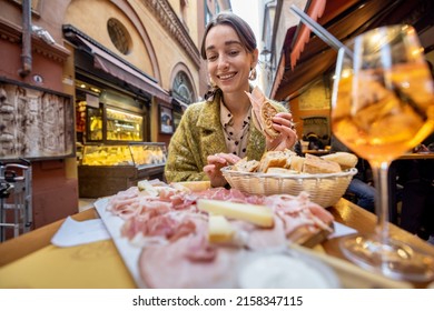 Woman eating italian meat appetizer, various sliced meat and cheese with bread and Aperol Spritz at bar or restaurant outdoors. Concept of Italian lifestyle and gastronomy - Powered by Shutterstock