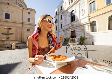 Woman eating italian pasta and drinking wine at restaurant on the street in Rome. Concept of Italian gastronomy and travel. Stylish woman with sunglasses and colorful hair shawl - Powered by Shutterstock