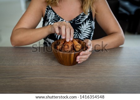 A woman eating Korean spicy chicken wings from a wooden bowl