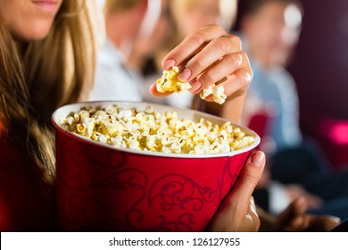 Woman Eating Large Container Of Popcorn In Cinema Or Movie Theater