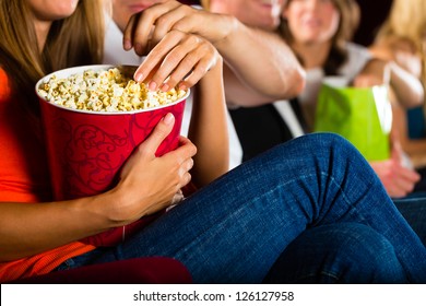 Woman Eating Large Container Of Popcorn In Cinema Or Movie Theater