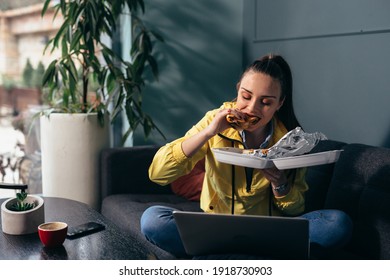 Woman Eating Lunch While Sitting On Sofa And Using Laptop Computer At Her Home