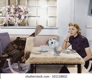 Woman eating at table with live turkey