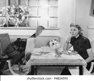 Woman eating at table with live turkey