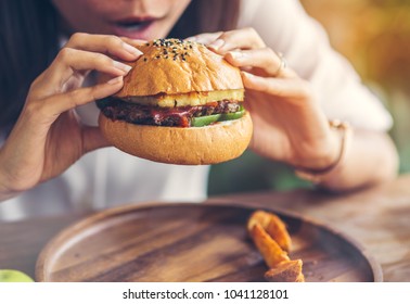 Woman Eating Meat Burger In Restaurant.