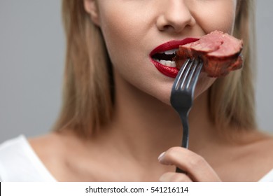 Woman Eating Meat. Closeup of Healthy Hungry Girl With Beautiful Face, Red Lips Eats Delicious Grilled Meat. Female Mouth Biting Piece Of Tasty Beef Steak On Fork. Nutrition Concept. High Resolution