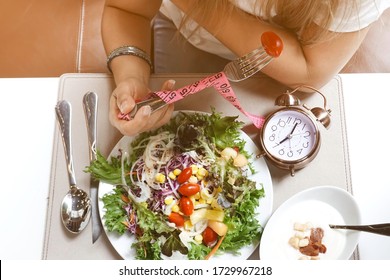 Woman Eating In The Morning With Alarm Clock Of Intermittent Fasting And Healthy Food And Salad Concept.