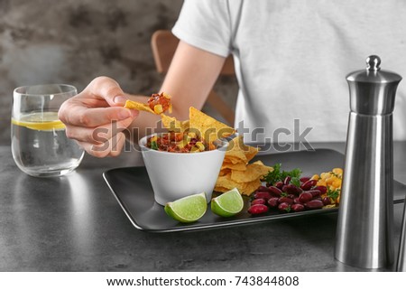 Woman eating nacho with chili con carne in cafe