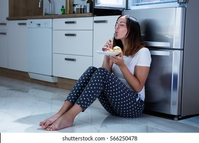 Woman Eating Near Refrigerator
