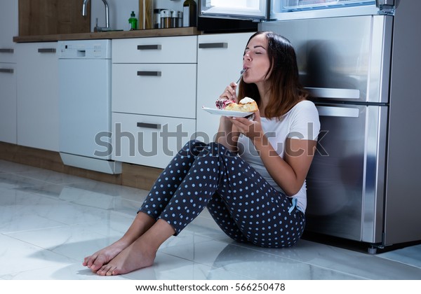 Woman Eating Near\
Refrigerator