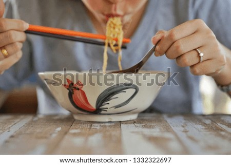woman is eating noodle by use chopsticks