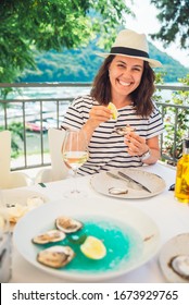woman eating oysters in outdoors restaurant at sunny summer weather