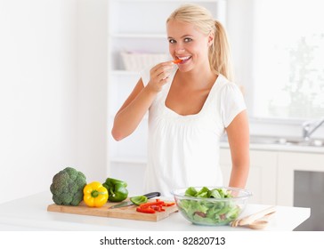 Woman eating pepper in her kitchen - Shutterstock ID 82820713