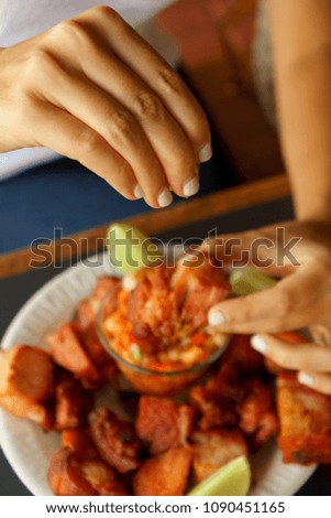 Woman eating pieces of pork with lemon and bbq.