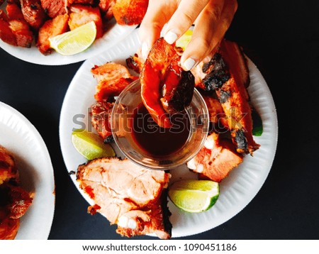 Woman eating pieces of pork with lemon and bbq.