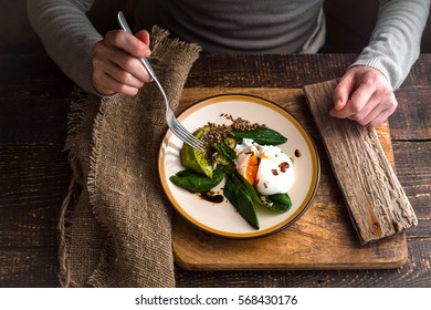 Woman Eating Poached Egg With Avocado Cream Top View