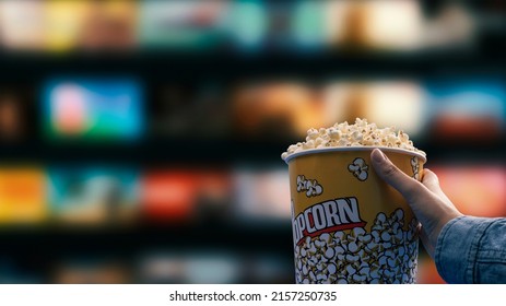 Woman eating popcorn and watching videos on demand at home on TV - Powered by Shutterstock