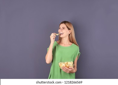 Woman Eating Potato Chips On Grey Background