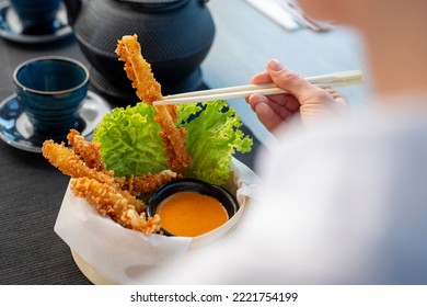 Woman Is Eating Prawns In Batter In A Bamboo Basket.
Traditional Japanese Food Eaten In A Restaurant.