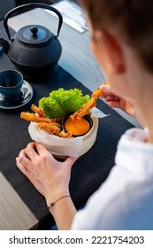 Woman Is Eating Prawns In Batter In A Bamboo Basket.
Traditional Japanese Food Eaten In A Restaurant.