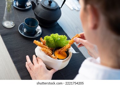 Woman Is Eating Prawns In Batter In A Bamboo Basket.
Traditional Japanese Food Eaten In A Restaurant.