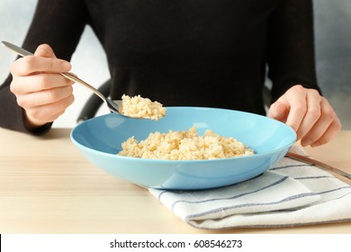 Woman Eating Quinoa Porridge At Kitchen Table