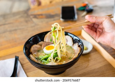 Woman Eating A Ramen Japanese Noodle Soup In A Black Color Ramen Bowl.