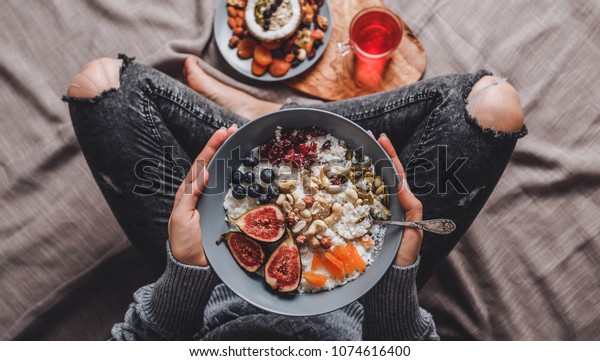 Woman eating Rice coconut
porridge with figs, berries, nuts and coconut milk in plate.
Healthy breakfast ingredients. Clean eating, vegan diet, comfort
food concept
