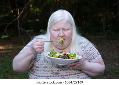 Woman Eating A Salad Of Romaine Lettuce, Croutons, Shredded Cheddar Cheese, And Tomato From A White Plate