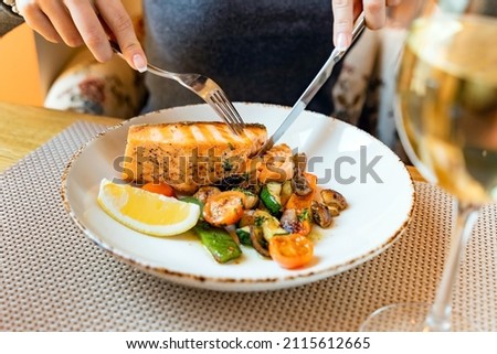 woman eating salmon steak with roasted vegetables