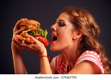 Woman Eating Sandwich. Girl With Pleasure Eats Burger After Diet. She Opened Her Mouth, Holding A Hamburger On His Outstretched Hands And Closed Her Eyes. Student With Meal On Black Background.